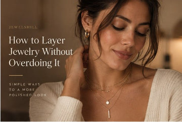 Woman in a cream knit wearing layered necklaces and a hoop earring.